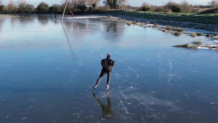 Skaters take to ice on frozen flooded field in Cambridgeshire