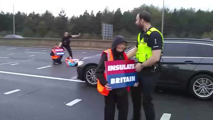 Insulate Britain protesters walk between lanes of oncoming traffic on M25