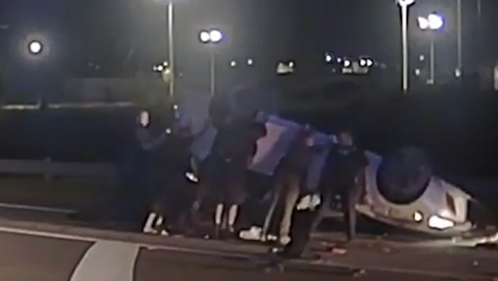'Good samaritans' help police officers lift flipped car to save trapped driver