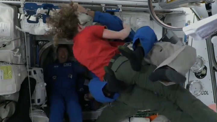 Astronauts hug after arriving at space station on SpaceX capsule