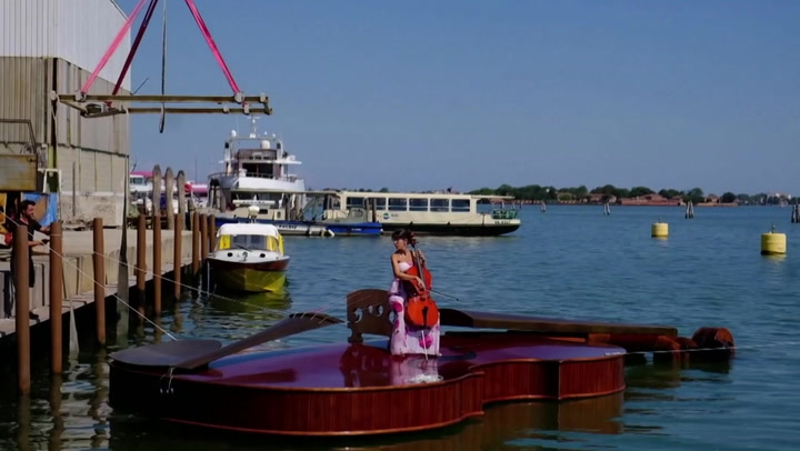 Cellist plays song on massive violin-shaped boat in Venice