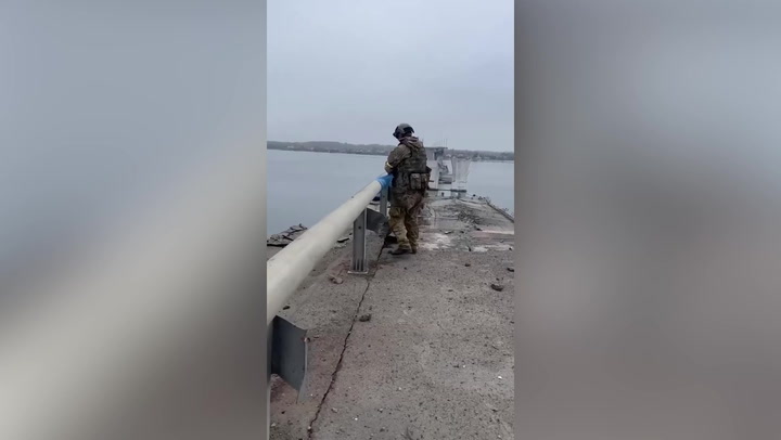 Ukrainian soldiers tie flag to damaged Antonovsky bridge in Kherson Oblast