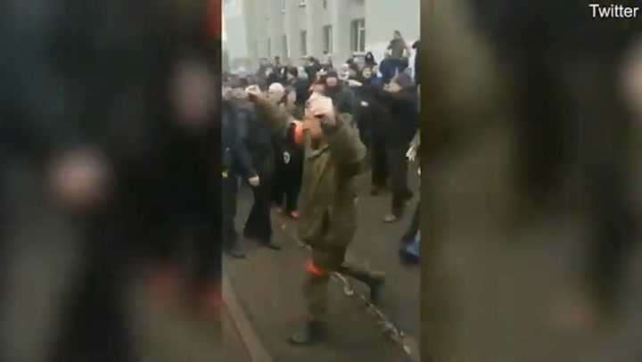 Soldado ruso camina con granadas en mano entre multitud de ucranianos
