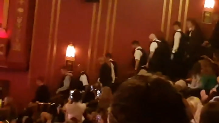Crowd cheers as police escort Grease theatregoers from London audience
