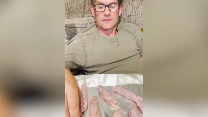 Woman films boyfriend snacking on raw sausages