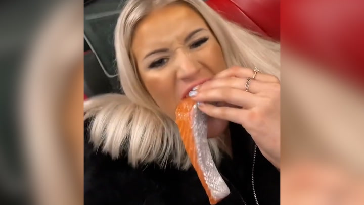 Woman devours raw salmon fillet on bus