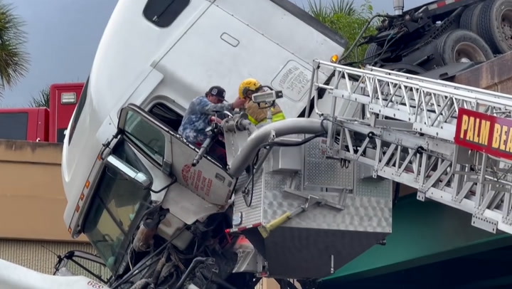 Moment driver rescued from dangling truck over busy highway