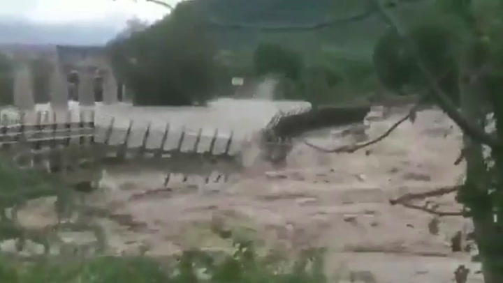 Giant bridge collapses after heavy rainfall causes raging river to flood