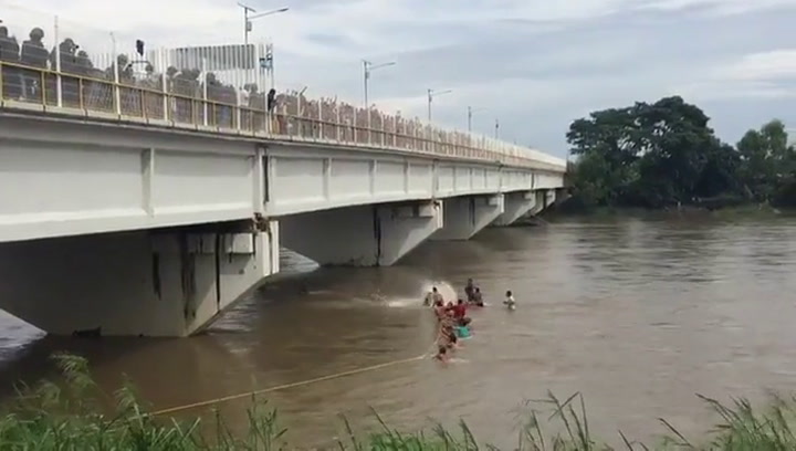 Migrantes hondureños se lanzan desde un puente al río Suchiate - Fuente: Twitter