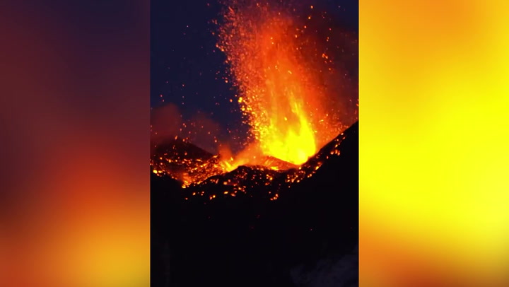 Mount Etna spits lava and billows smoke into night sky
