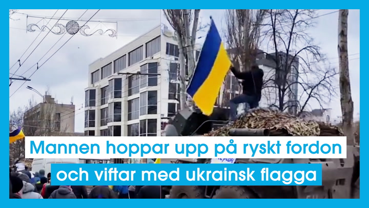 Mannen hoppar upp på ryskt fordon och viftar med ukrainsk flagga