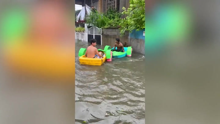 Locals play in boats on flooded road amid typhoon aftermath in the Philippines