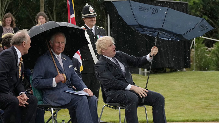 Boris Johnson struggles with umbrella while sat next to Prince Charles