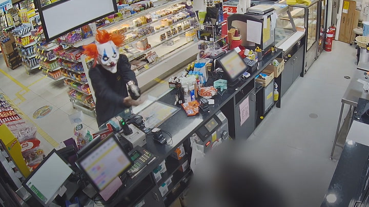 Terrifying moment robber in clown mask points weapon at shop worker