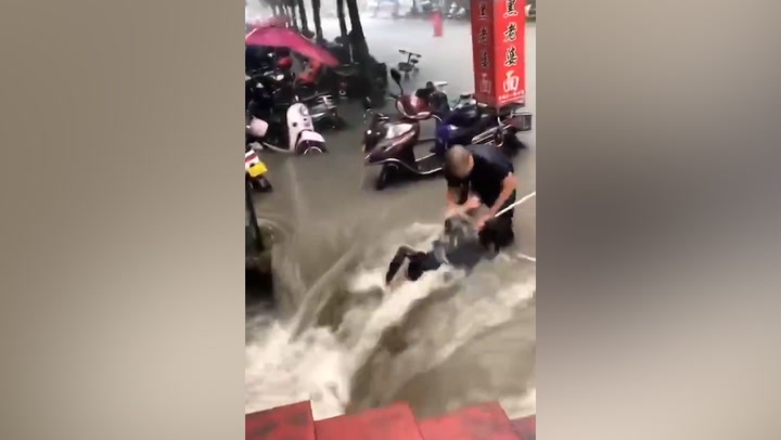 Woman pulled out of raging China flood by rope in dramatic rescue  
