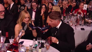 Roman Kemp and Kylie Minogue drink out of shoes at Brit Awards 2024