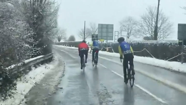 Cyclists brave wintry scenes in Gloucestershire as snowfall blankets west England