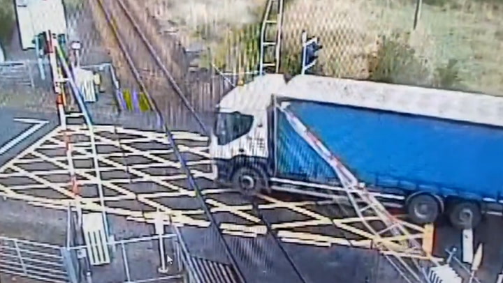 Moment lorry drives through descending railway barrier