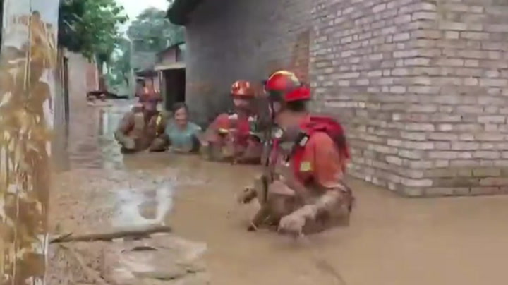 Rescuers wade through waist-high mud to evacuate flooded homes in China