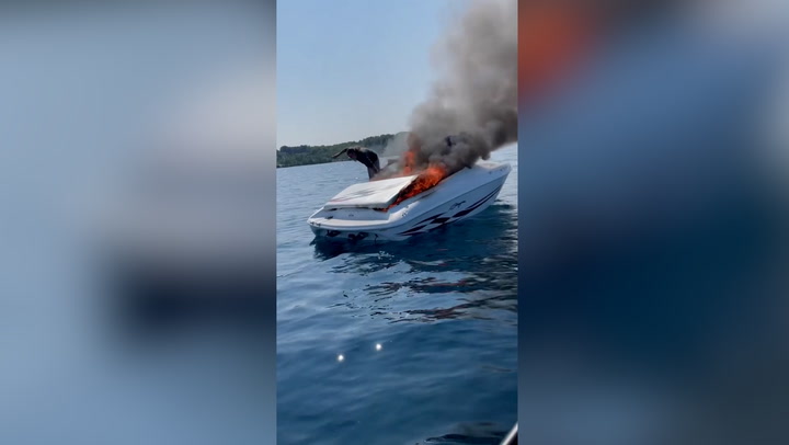 Moment boat bursts into flames as crew leap to safety into Lake Michigan