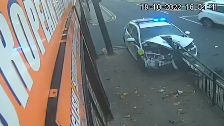 Moment police car slams into railing after colliding with another vehicle