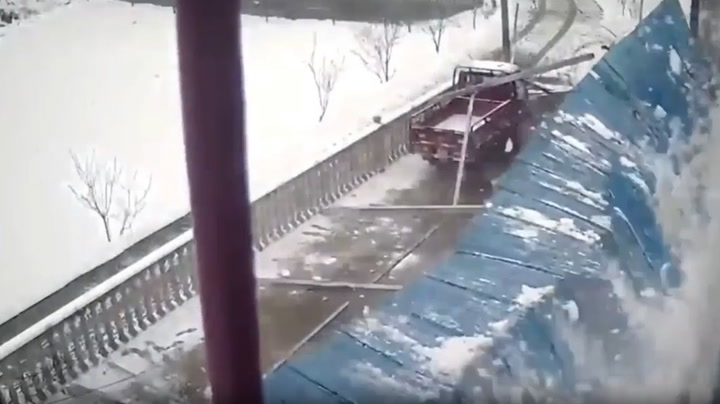 Shed roof weighed down by snow collapses narrowly missing driver