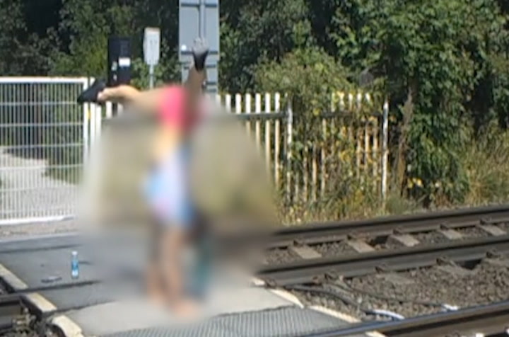 Two teenage girls do handstands on busy train tracks