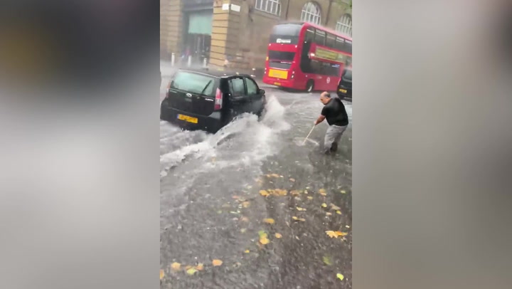 Man brushes away water as flash floods hit King's Cross
