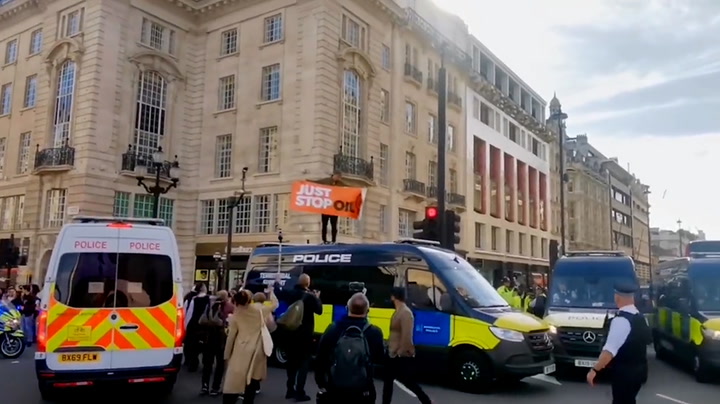 Just Stop Oil protester climbs on top of police van in London