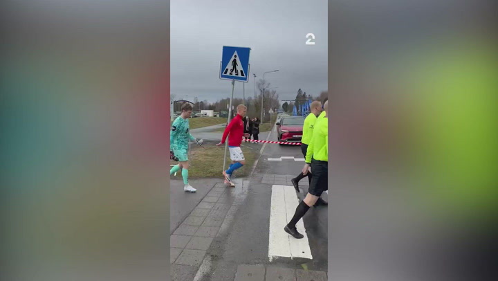 Acontece na Noruega: jogadores atravessam rua para entrarem em campo