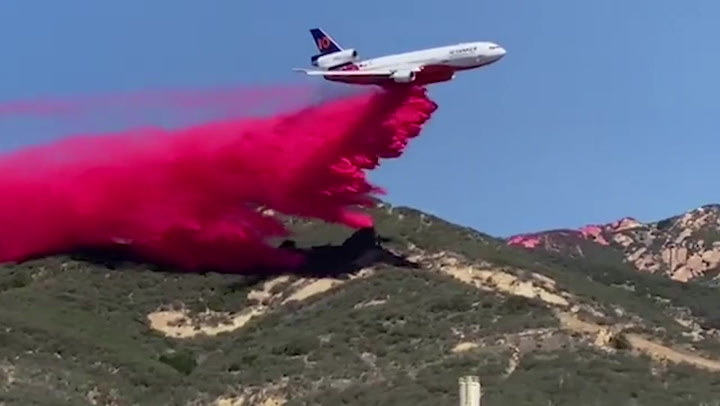 California fire department jet aircraft drops fire retardant on wildfire burn area