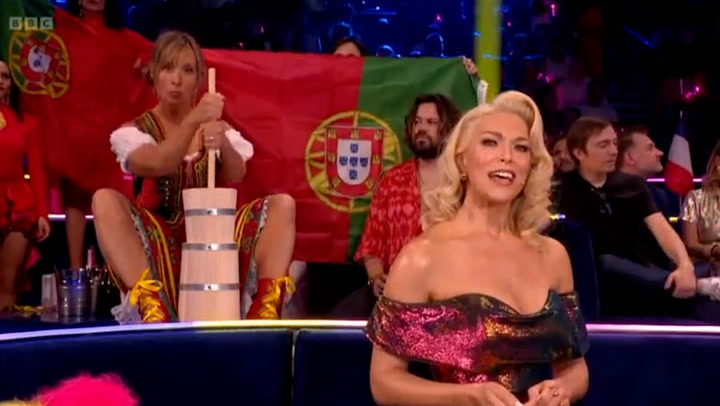 Mel Giedroyc churns butter behind Hannah Waddington at Eurovision