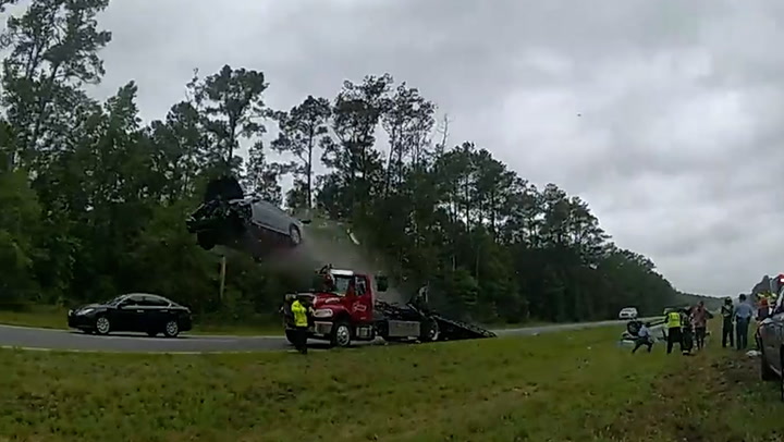 Car flies through the air after launching off back of stationary tow truck